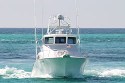 deep-sea-2 A white motorboat traveling quickly on clear blue-green ocean water, creating waves as it moves forward. The sky is clear in the background.